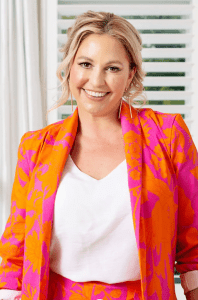 An Australian designer brand featuring a vibrant orange and pink floral blazer and matching high-waisted shorts, styled with a white blouse and paired with bold pink heels. A chic and lively look that embodies Australian premium fashion.