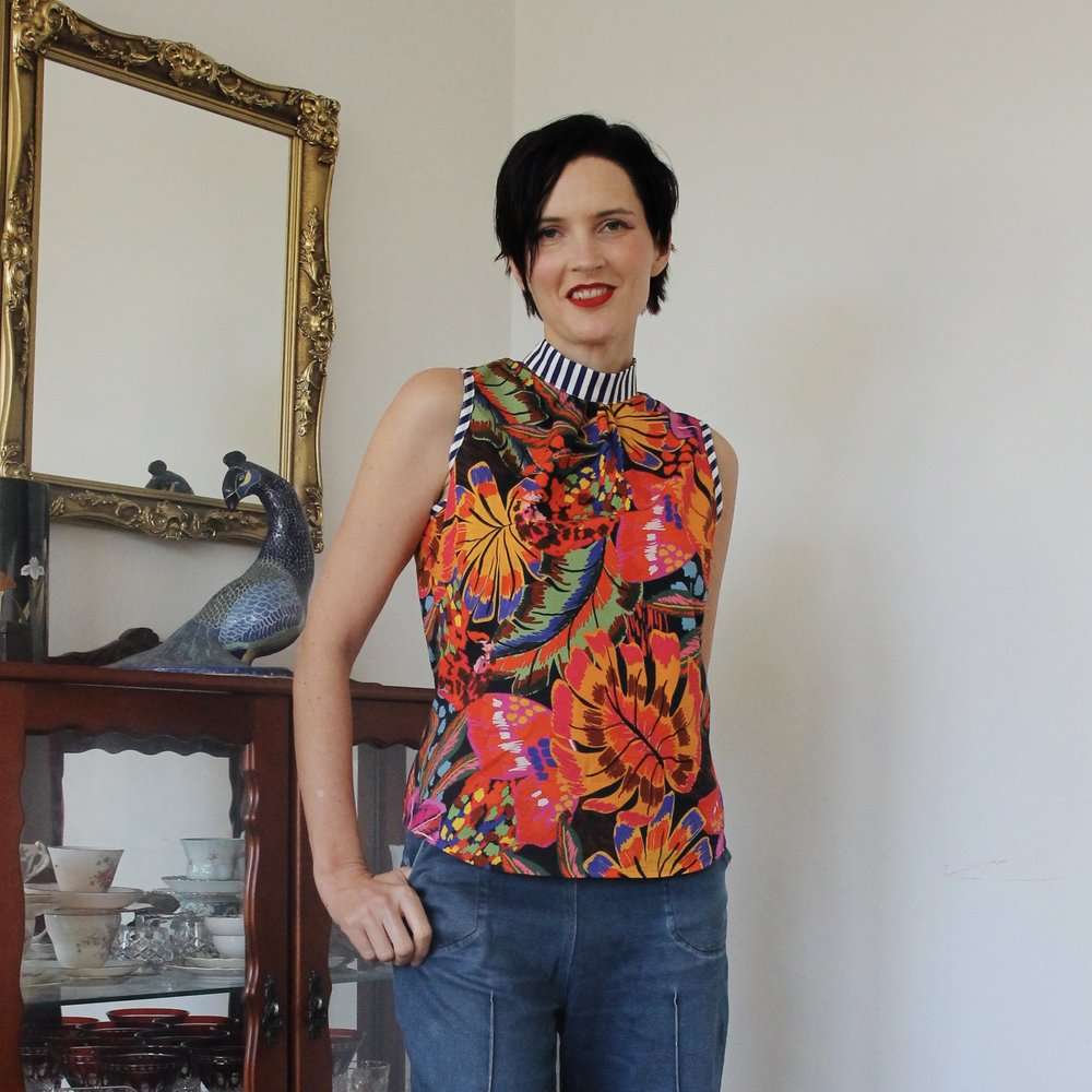Sleeveless top with a bright tropical floral pattern and striped collar detail