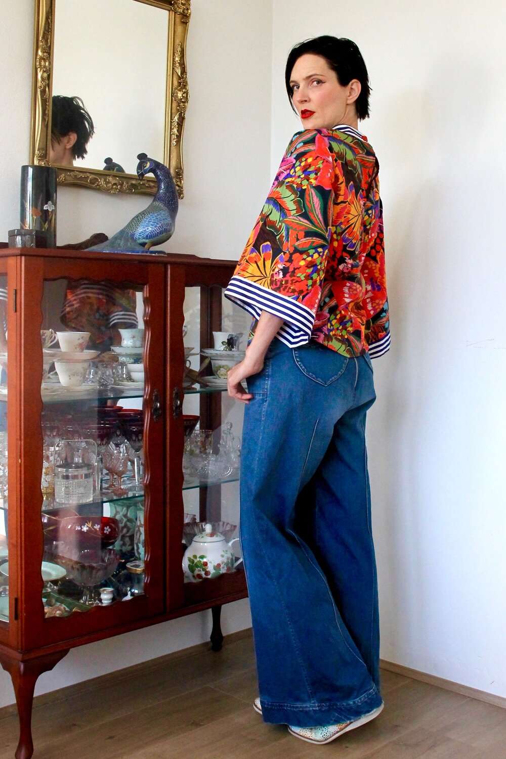 Bold tropical floral blouse featuring vibrant orange, purple, and green hues, paired with a red skirt.