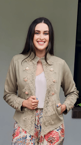 Austere Suede Touch Jacket in toffee , featuring intricate lace detailing along the front and cuffs, adorned with gold buttons for a refined, elegant finish.