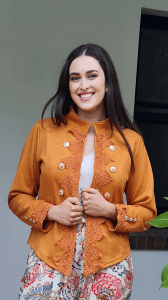 Austere Suede Touch Jacket in orange , featuring intricate lace detailing along the front and cuffs, adorned with gold buttons for a refined, elegant finish.