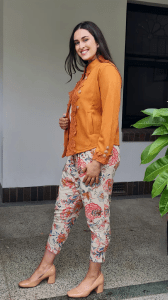 Austere Suede Touch Jacket in orange, featuring intricate lace detailing along the front and cuffs, adorned with gold buttons for a refined, elegant finish.