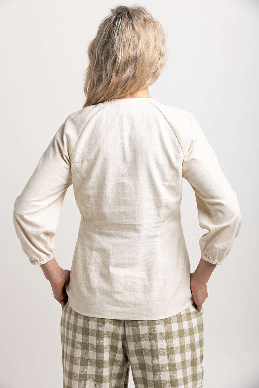 Cream-colored blouse with long sleeves, paired with relaxed-fit green gingham wide-leg pants, capturing a classic, sustainable style.