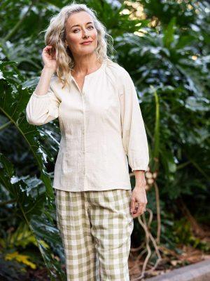 Cream-colored blouse with long sleeves, paired with relaxed-fit green gingham wide-leg pants,emphasizing Colouron Cotton's slow fashion values.