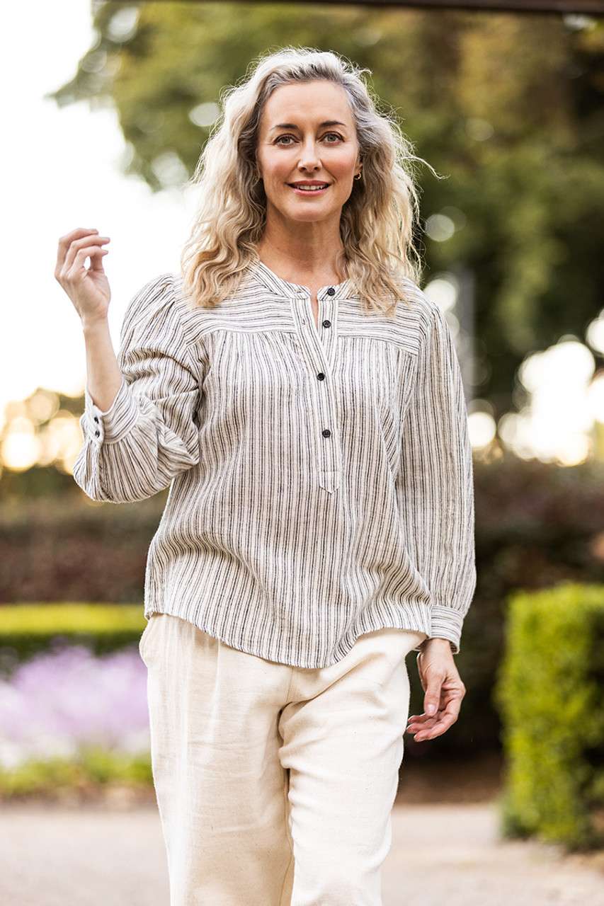 Natural-toned striped blouse with black buttons, featuring gathered details at the yoke, emphasizing Colouron Cotton's slow fashion values.