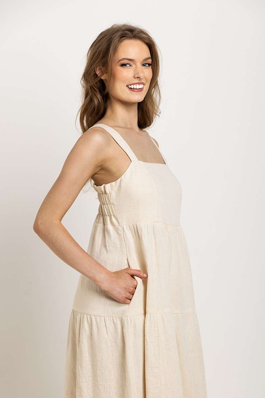 Cream, tiered midi dress with wide straps and pockets, perfect for an easy-going, sustainable wardrobe staple.