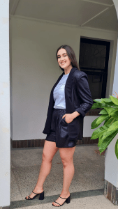 a black blazer and matching shorts, both with a subtle herringbone pattern that adds a hint of shimmer. This outfit from Astor and Tyne exemplifies a blend of professional and relaxed style, suitable for versatile day-to-night wear.