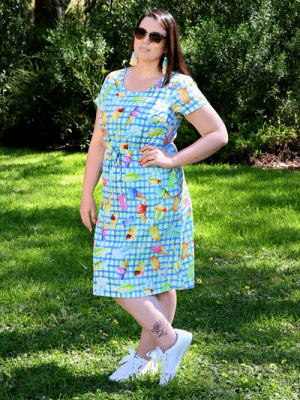 Woman wearing a green and blue dress with a colorful abstract print featuring fruit and ice-cream illustrations, styled for a playful, sunny-day look. Christmas haul