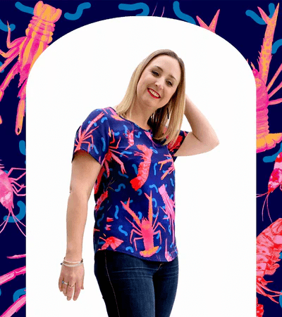A close-up view of a textile print depicting pink and red crustaceans, including lobsters and shrimp, on a deep blue background, with wavy line details that give a playful, underwater feel. Designed by Australian designer brand Streborclothing.