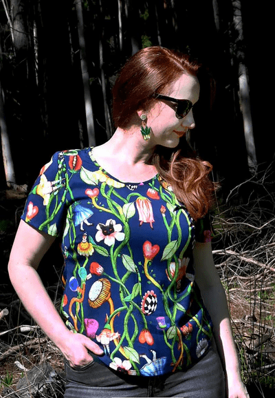 Woman in a forest scene wearing a dark blue dress with a lively floral and vine print, blending earthy elements with an artistic twist in nature-inspired surroundings. Designed by Australian designer brand Streborclothing.